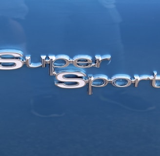 The image features the words 'Super Sport' in shiny, metallic lettering. The background is a smooth, glossy blue surface, likely part of a vehicle.