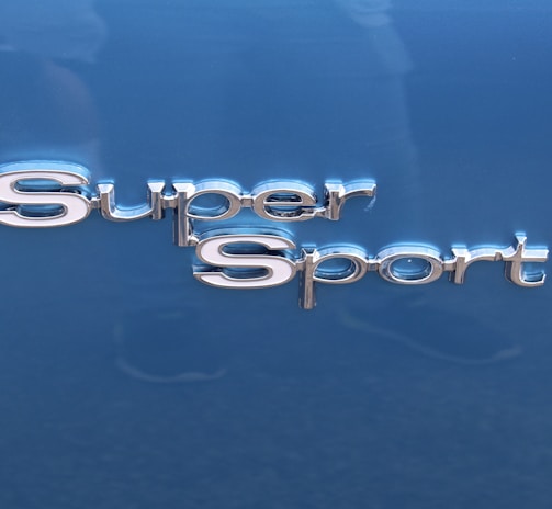 The image features the words 'Super Sport' in shiny, metallic lettering. The background is a smooth, glossy blue surface, likely part of a vehicle.